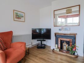 A living room with a TV and a fireplace at St Helena in Charmouth