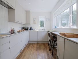 A kitchen with cabinets, counter space, and bar stools at St Helena in Charmouth