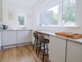 A kitchen with a sink and bar stools at St Helena in Charmouth