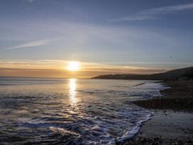 A beach with waves and a sunset at St Helena in Charmouth