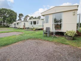 A row of mobile homes with outdoor chairs and tables on grass at 2 Old Orchard in Brockton near Much Wenlock