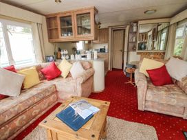 A living area with patterned sofas and colorful cushions a wooden coffee table and an open doorway at 2 Old Orchard in Brockton near Much Wenlock