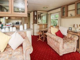 A living area with two upholstered sofas with pillows a small round dining table with chairs and a kitchen counter with canisters at 2 Old Orchard in Brockton near Much Wenlock