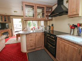 A kitchen with wooden cabinets stove and utensils with a view of a living room at 2 Old Orchard Brockton near Much Wenlock