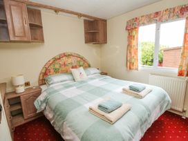 A bedroom with a double bed and towels on it next to a window with floral curtains at 2 Old Orchard Brockton near Much Wenlock