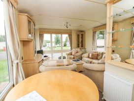 A living area with armchairs a sofa a round wooden table and a cabinet with display shelves at 4 Old Orchard Brockton near Much Wenlock
