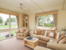 A sitting room with armchairs and a sofa around a coffee table at 4 Old Orchard in Brockton near Much Wenlock