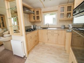 A kitchen with wooden cabinets a gas stove a sink and a window at 4 Old Orchard in Brockton near Much Wenlock
