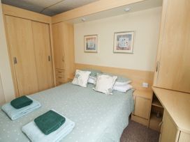 A bedroom with a double bed with teal bedding and towels and wooden wardrobes at 4 Old Orchard in Brockton near Much Wenlock