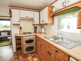 A kitchen with wooden cabinets a stove a double oven a sink with a drying rack and a window at 5 Old Orchard in Brockton near Much Wenlock