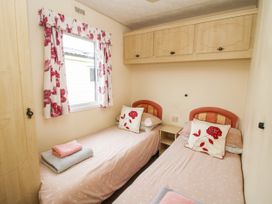 A small bedroom with two single beds and floral curtains at 5 Old Orchard Brockton near Much Wenlock