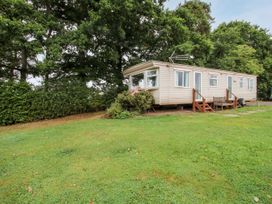 A mobile home with steps and bench outside surrounded by grass and trees at 7 Old Orchard in Brockton near Much Wenlock