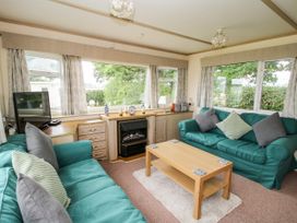 A living room with teal sofas facing a wooden coffee table and a fireplace at 7 Old Orchard in Brockton near Much Wenlock