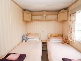 A bedroom with two single beds with stuffed toys and a small window at 7 Old Orchard in Brockton near Much Wenlock