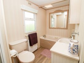 A bathroom with a toilet, bathtub, sink, mirror, and a blue and white pitcher at 7 Old Orchard in Brockton near Much Wenlock