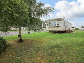 A caravan on a grassy area near a tree and a gravel path at 8 Old Orchard in Brockton near Much Wenlock