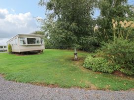 A mobile home on a grassy plot with a tree and garden at 8 Old Orchard in Brockton near Much Wenlock