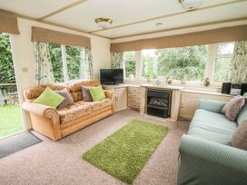 A living room with two sofas a green rug a fireplace and large windows at 8 Old Orchard in Brockton near Much Wenlock
