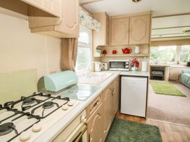A kitchen area with a gas stove, sink, toaster, microwave, refrigerator, and cabinets at 8 Old Orchard in Brockton near Much Wenlock