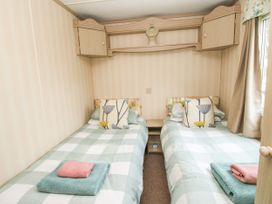 A bedroom with two single beds with green and white checkered bedding and floral pillows at 8 Old Orchard in Brockton near Much Wenlock