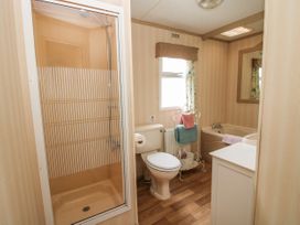 A bathroom with a shower enclosure toilet bathtub towel stand and a window at 8 Old Orchard in Brockton near Much Wenlock