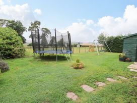 A backyard with a trampoline swing set shed and potted plants at 8 Old Orchard in Brockton near Much Wenlock