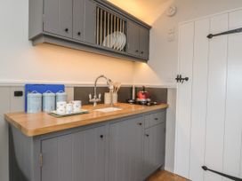 A kitchen with grey cabinets wooden countertop and a sink next to a red kettle on the stove at Coraldie in Laggan near Newtonmore