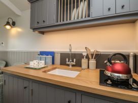A kitchen countertop with a sink red kettle utensils and cabinets at Coraldie in Laggan near Newtonmore