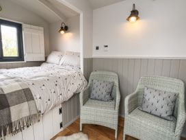 A bedroom with a bed in an alcove and two wicker chairs with cushions at Coraldie in Laggan near Newtonmore