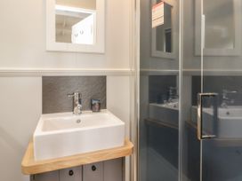 A bathroom sink with a faucet and soap dispenser next to a glass shower door at Coraldie Laggan near Newtonmore