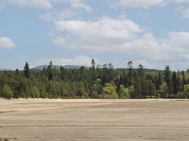 A sandy foreground with a forest of trees and hills under a cloudy sky at Coraldie in Laggan near Newtonmore