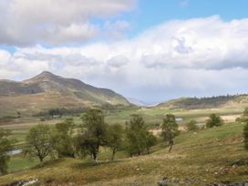 A rural landscape with hills trees and patches of water under a cloudy sky at Coraldie Laggan near Newtonmore