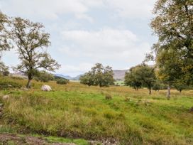 An open grassy field with scattered trees and hills in the background at Coraldie in Laggan near Newtonmore