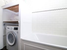 A bathroom with a washing machine and a bathtub at Faraway in Rhosneigr