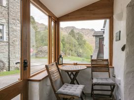 A conservatory with a table and chairs at Woodloft Cottage Elterwater near Chapel Stile