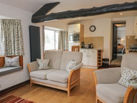 A living room with seating and kitchen appliances at Woodloft Cottage Elterwater near Chapel Stile