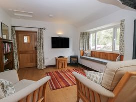 A living room with a television and bookshelf at Woodloft Cottage Elterwater near Chapel Stile