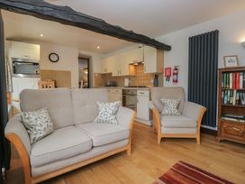 A living room with a sofa and kitchen area at Woodloft Cottage Elterwater near Chapel Stile