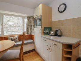 A kitchen with table, chairs, and appliances at Woodloft Cottage Elterwater near Chapel Stile