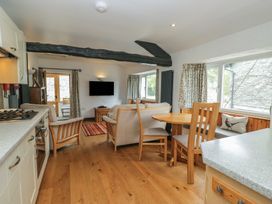 A living room with a table and chairs near the kitchen at Woodloft Cottage in Elterwater near Chapel Stile