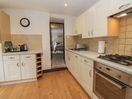 A kitchen featuring cabinets, stove, sink and doorway at Woodloft Cottage Elterwater near Chapel Stile