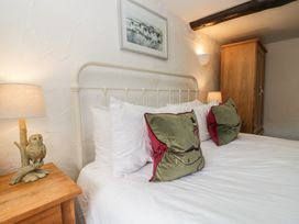 A bedroom with a bed, pillows, lamps, and a wardrobe at Woodloft Cottage Elterwater near Chapel Stile