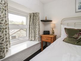 A bedroom with a window and bedside table at Woodloft Cottage Elterwater near Chapel Stile