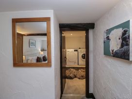 A hallway with a mirror, washing machine, and door at Woodloft Cottage Elterwater near Chapel Stile