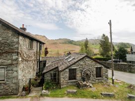 A view of stone buildings and mountains at Woodloft Cottage Elterwater near Chapel Stile