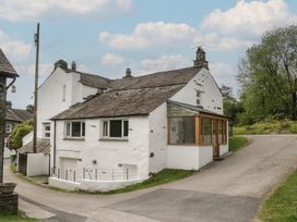 Exterior view of a house with a pathway and trees at Woodloft Cottage Elterwater near Chapel Stile