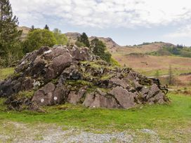 A rock formation with a sign in a park at Woodloft Cottage in Elterwater near Chapel Stile