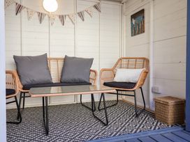 A seating area with rattan chairs and a glass table on a patterned rug at Kestrel Cottage Southwold