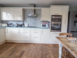 A kitchen with appliances and a dining table at Holly Lodge in Aldeburgh