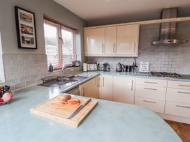 A kitchen with cabinets, sink, and cutting board at Holly Lodge in Aldeburgh
